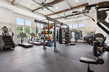 A spacious gym with a variety of equipment including treadmills, weights, and a bench press at Arcadia Cartersville Apartments, Cartersville, Georgia